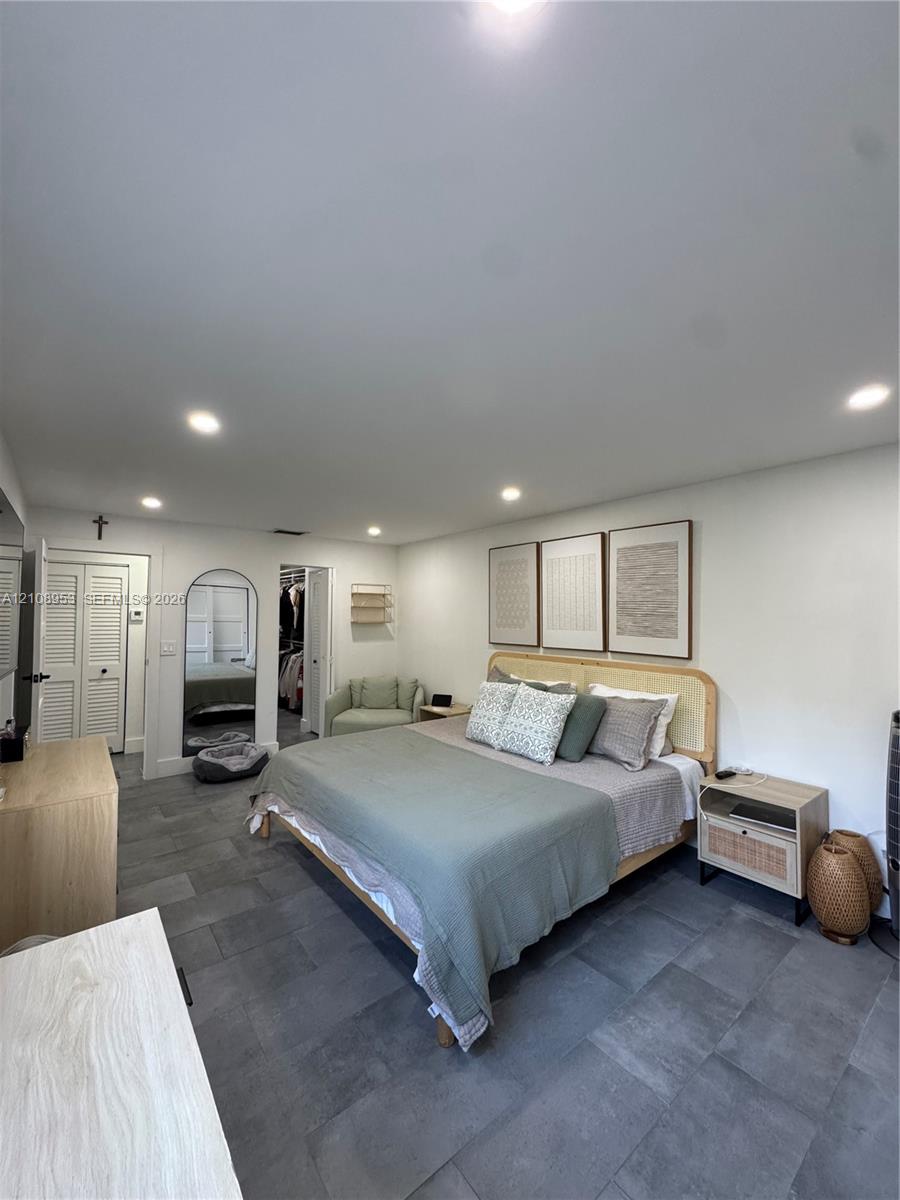 Large-format tile flooring, recessed ceiling lighting, and a built-in arched doorway featuring a mirror
