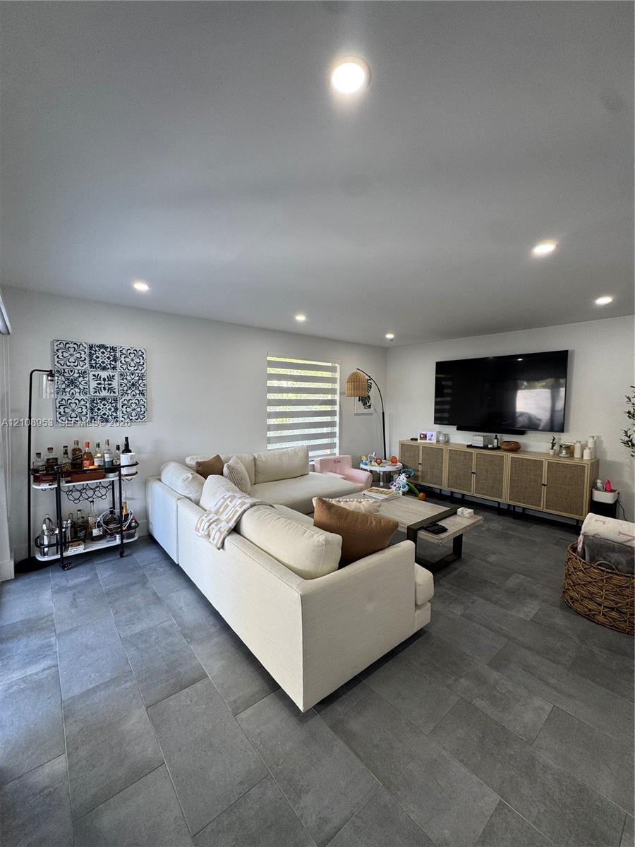 Living area featuring large-format tile flooring, recessed lighting, and a neutral color palette