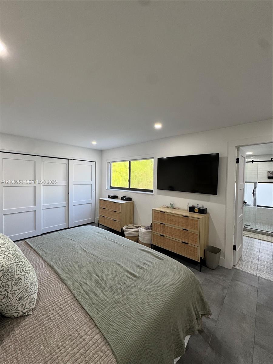 Recessed ceiling lighting, large-format tile flooring, oversized sliding closet doors, and a horizontal window