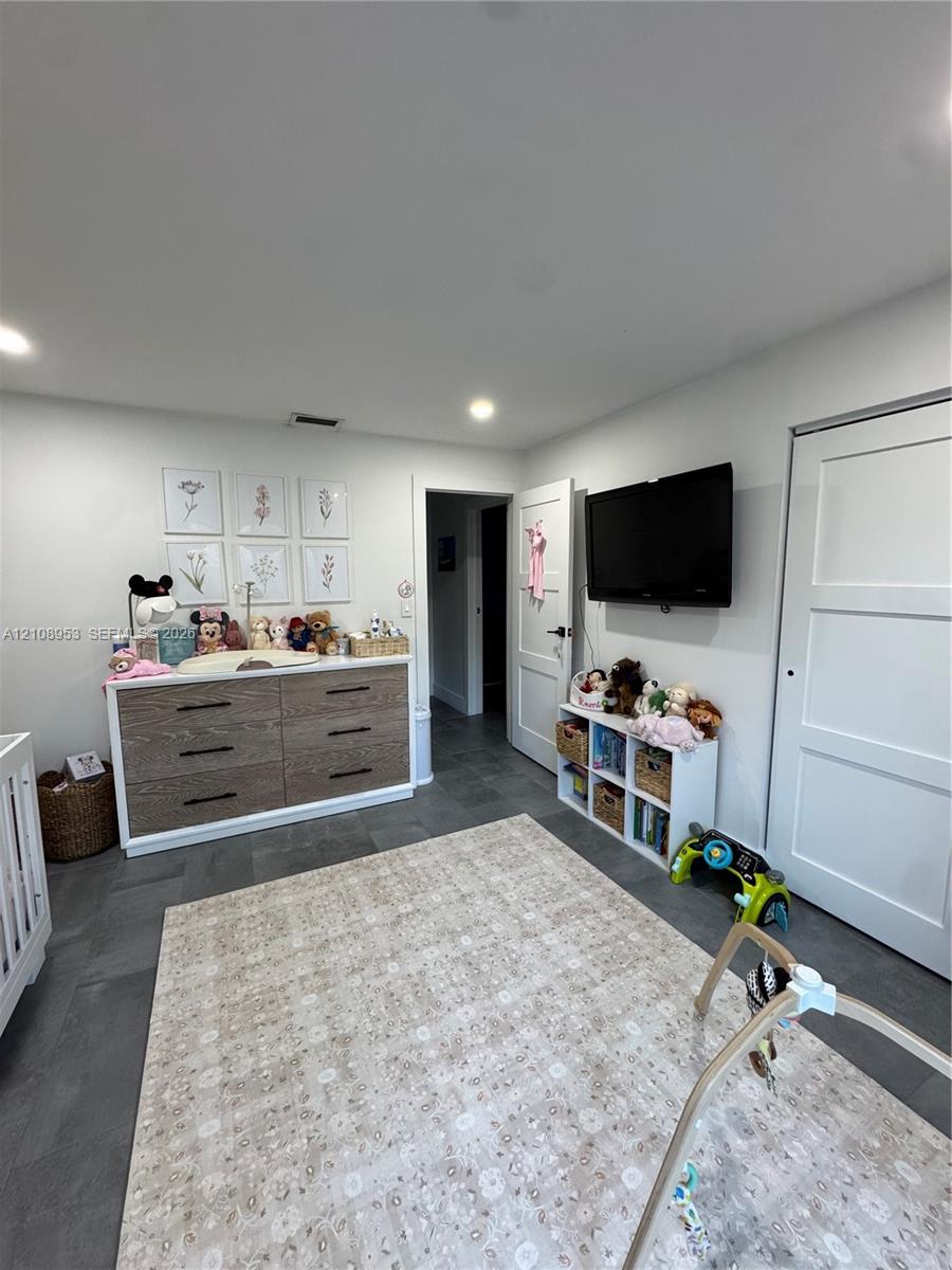Neutral-toned interior featuring recessed lighting, large-format grey tile flooring, and solid-core paneled doors
