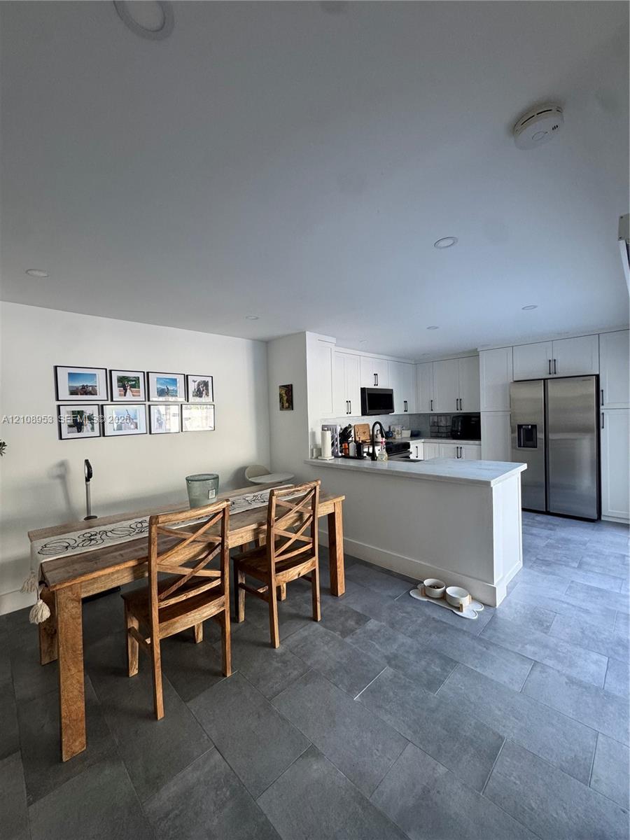 Kitchen featuring white shaker-style cabinetry, quartz countertops, a stainless steel side-by-side refrigerator, recessed lighting, and large-format tile flooring