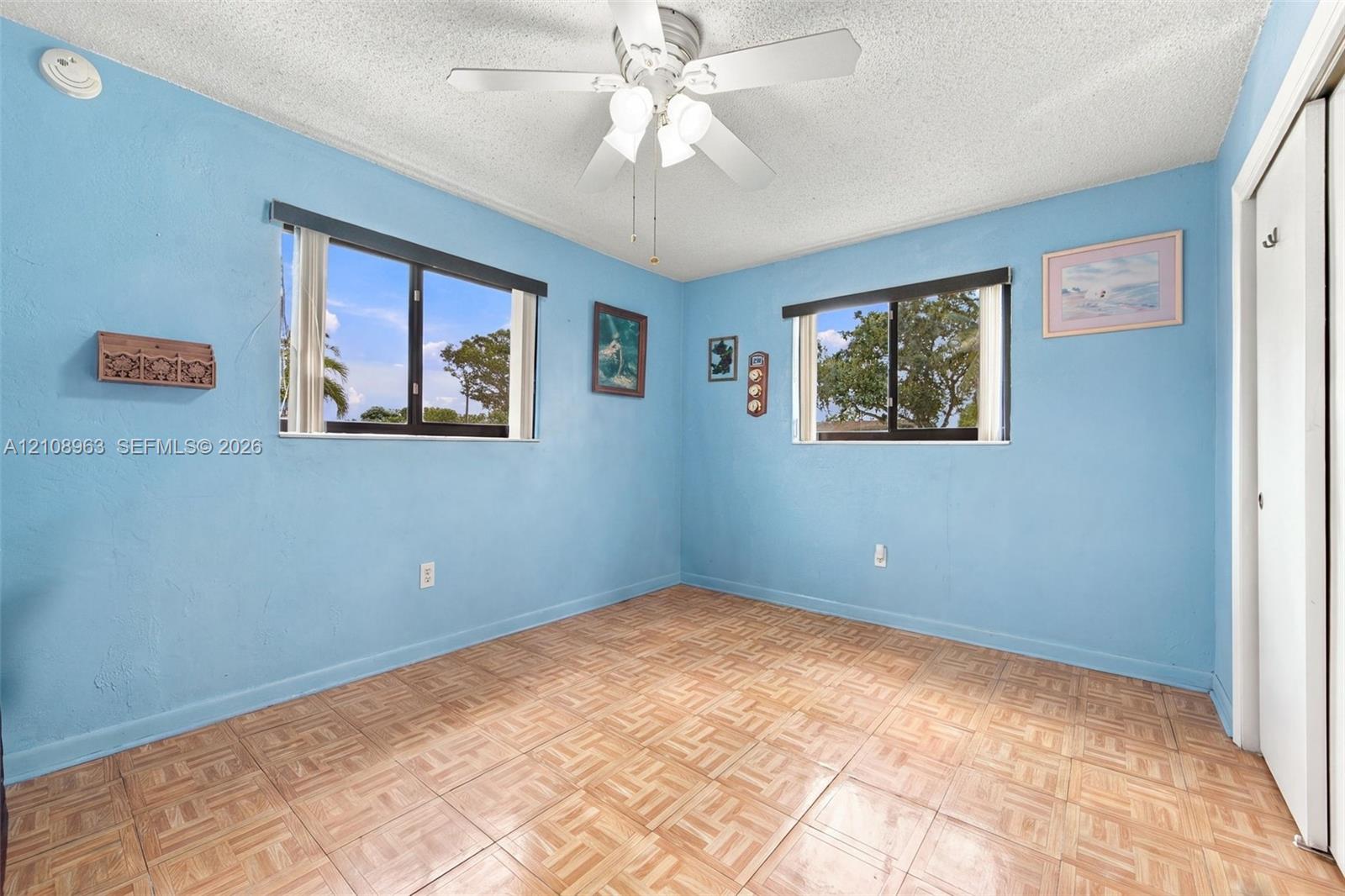 Interior room featuring parquet flooring, dual windows, and a ceiling-mounted light fixture with a fan