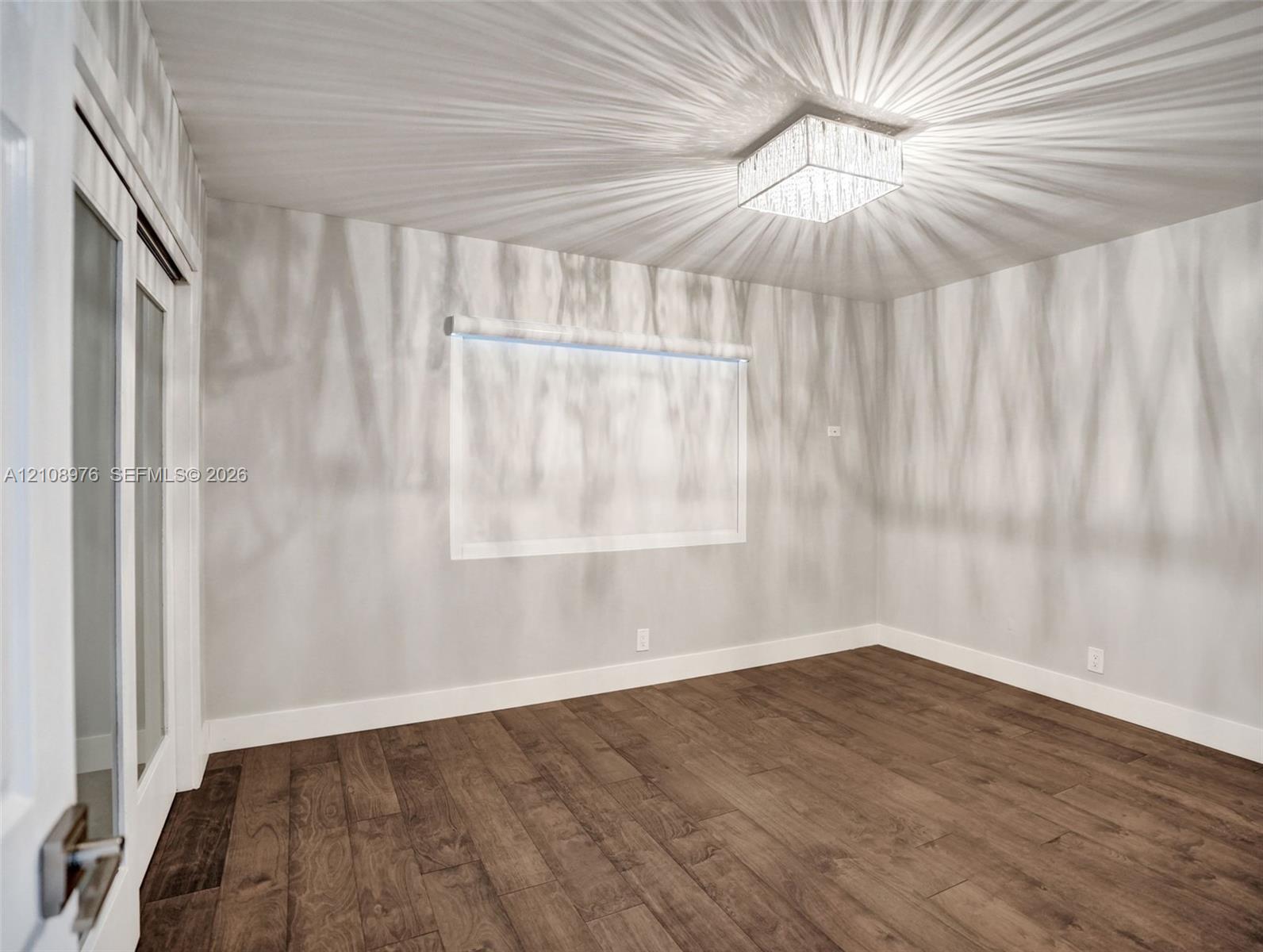 Room featuring wood-finish flooring, square crystal-accented flush mount ceiling light, and double doors with glass inserts