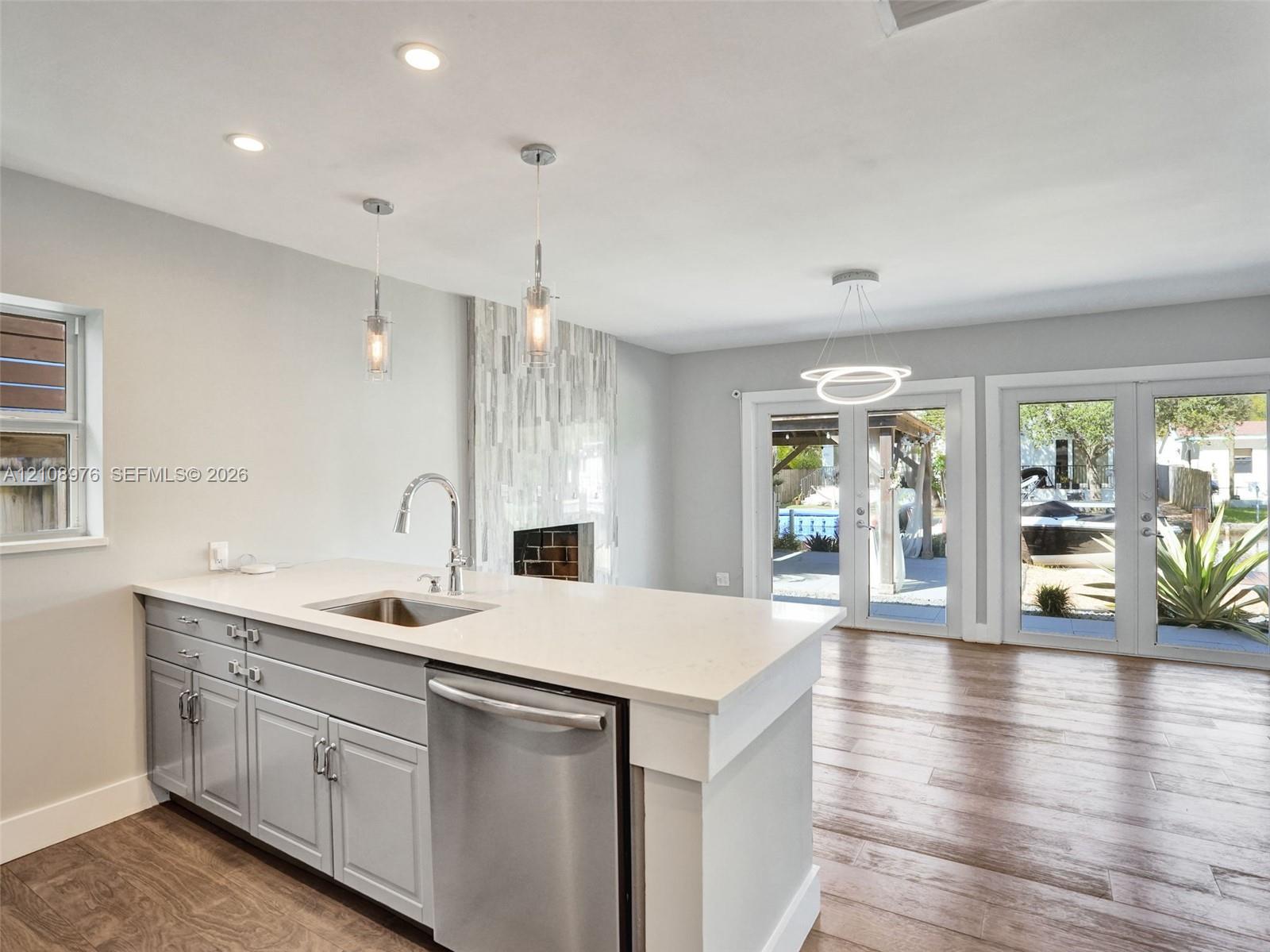 Kitchen island featuring light-toned cabinetry, a stone-finish countertop, stainless steel undermount sink, and recessed lighting