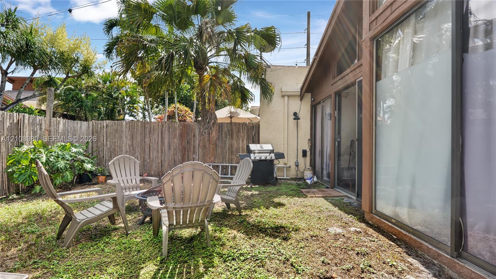 Fenced backyard featuring mature palm trees and full-height glass sliding doors