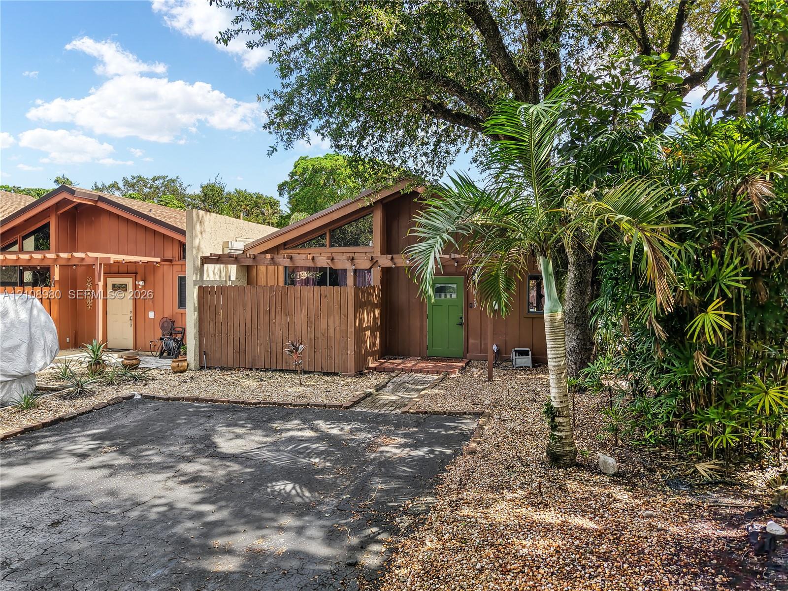Exterior featuring a wood-sided facade, pitched roofline with triangular clerestory windows, attached pergola, and gravel landscaping Exterior featuring a wood-sided facade, pitched roofline with triangular clerestory windows, attached pergola, and gravel landscaping