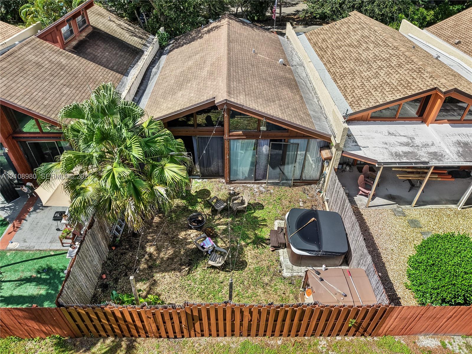 Private fenced backyard featuring a grassy lawn, mature palm tree, and a built-in spa