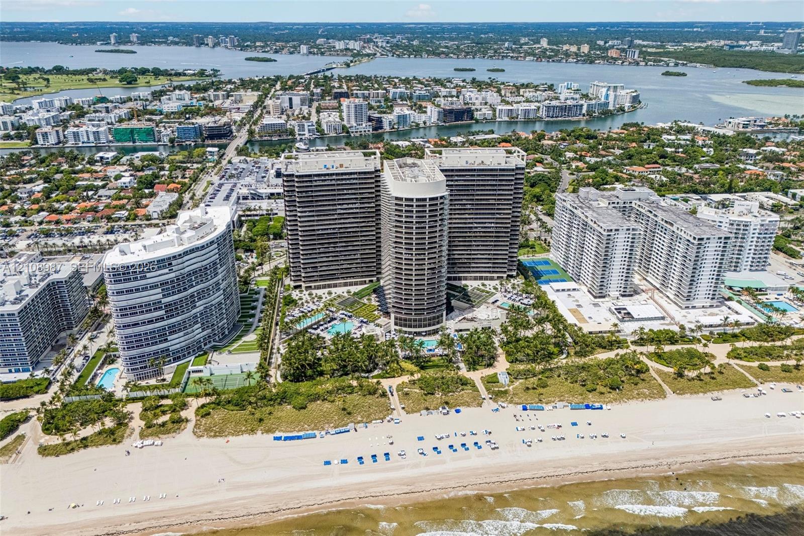 High-rise residential complex situated on a beachfront parcel featuring outdoor swimming pools, tennis courts, and landscaped grounds