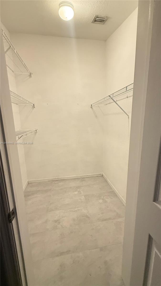 Walk-in closet featuring light-toned tile flooring, multi-level wire shelving, and a ceiling-mounted light fixture