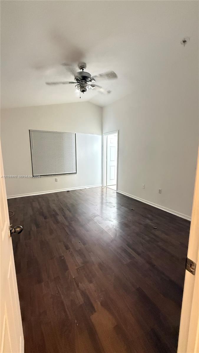 Room featuring vaulted ceilings, dark wood-finish flooring, and a ceiling fan
