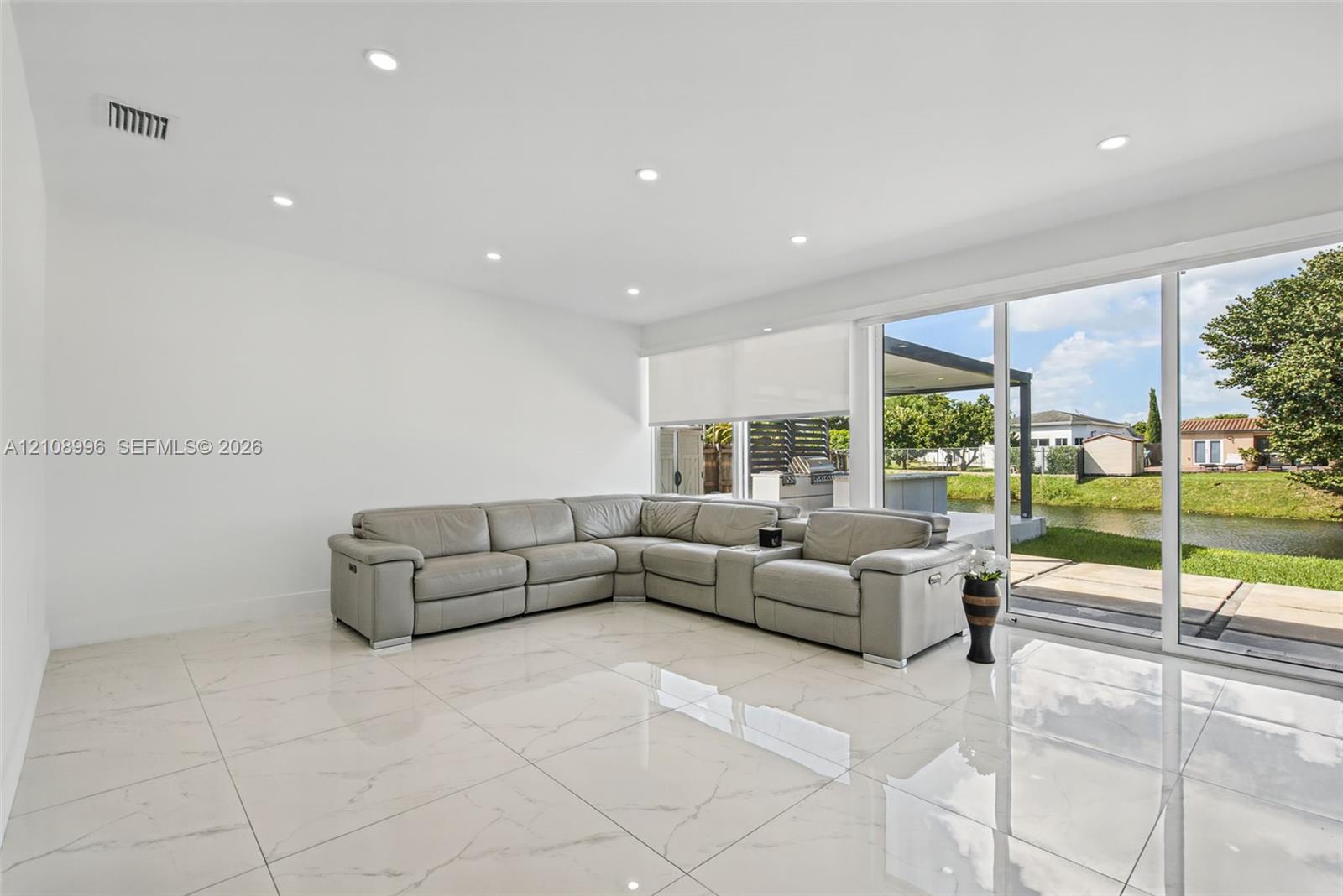 Large-format tile flooring, recessed ceiling lighting, and expansive glass sliding doors