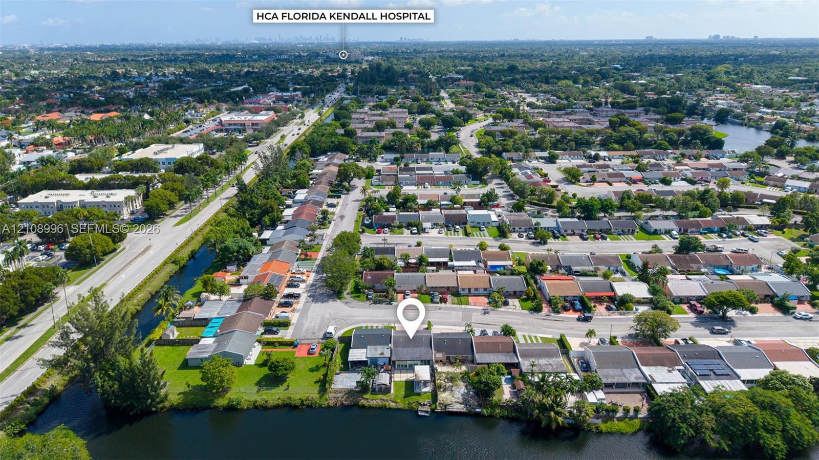 Aerial perspective of a residential property featuring a direct waterfront lot, private lawn area, and paved off-street parking