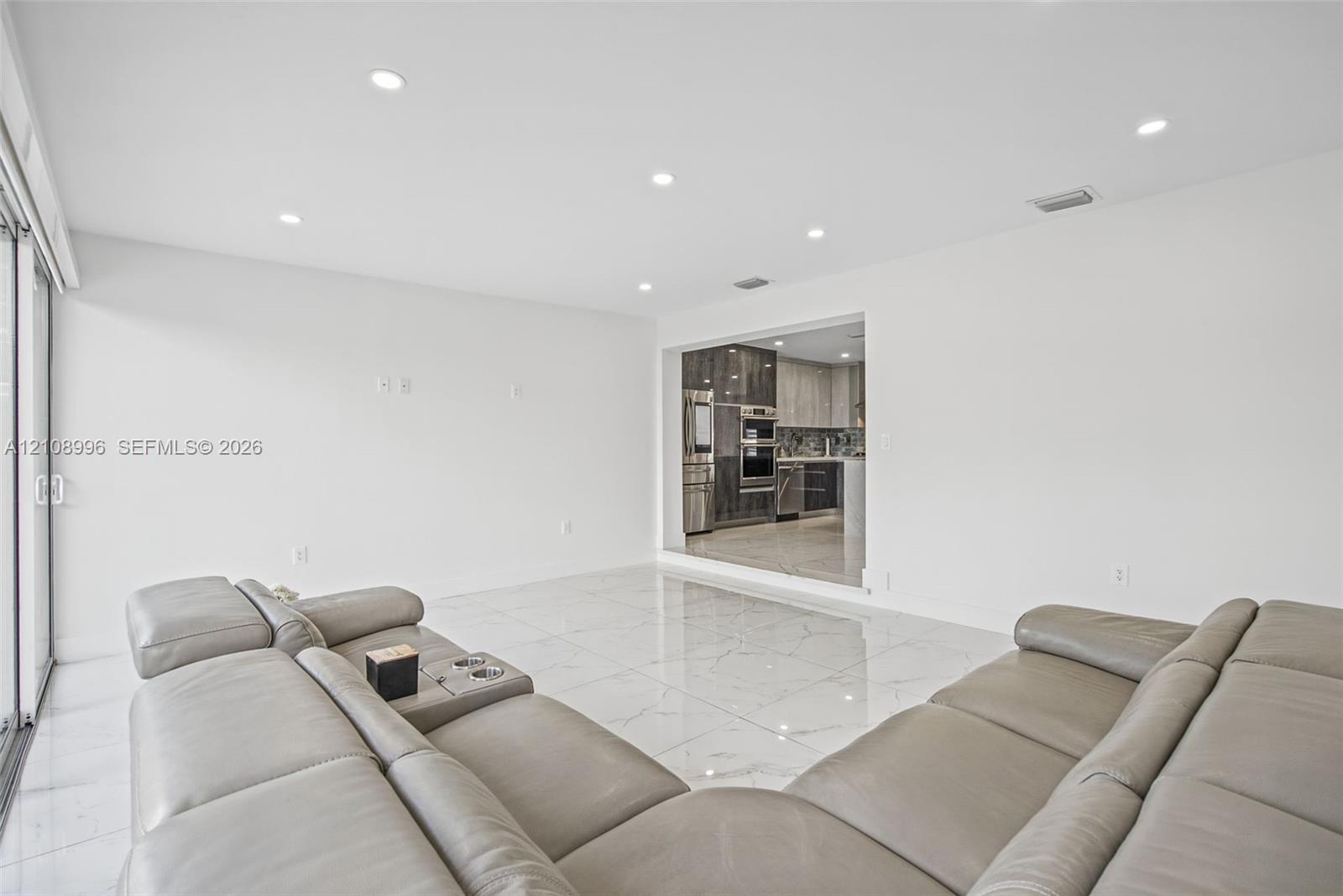Polished stone-finish flooring, recessed lighting, and large sliding glass door