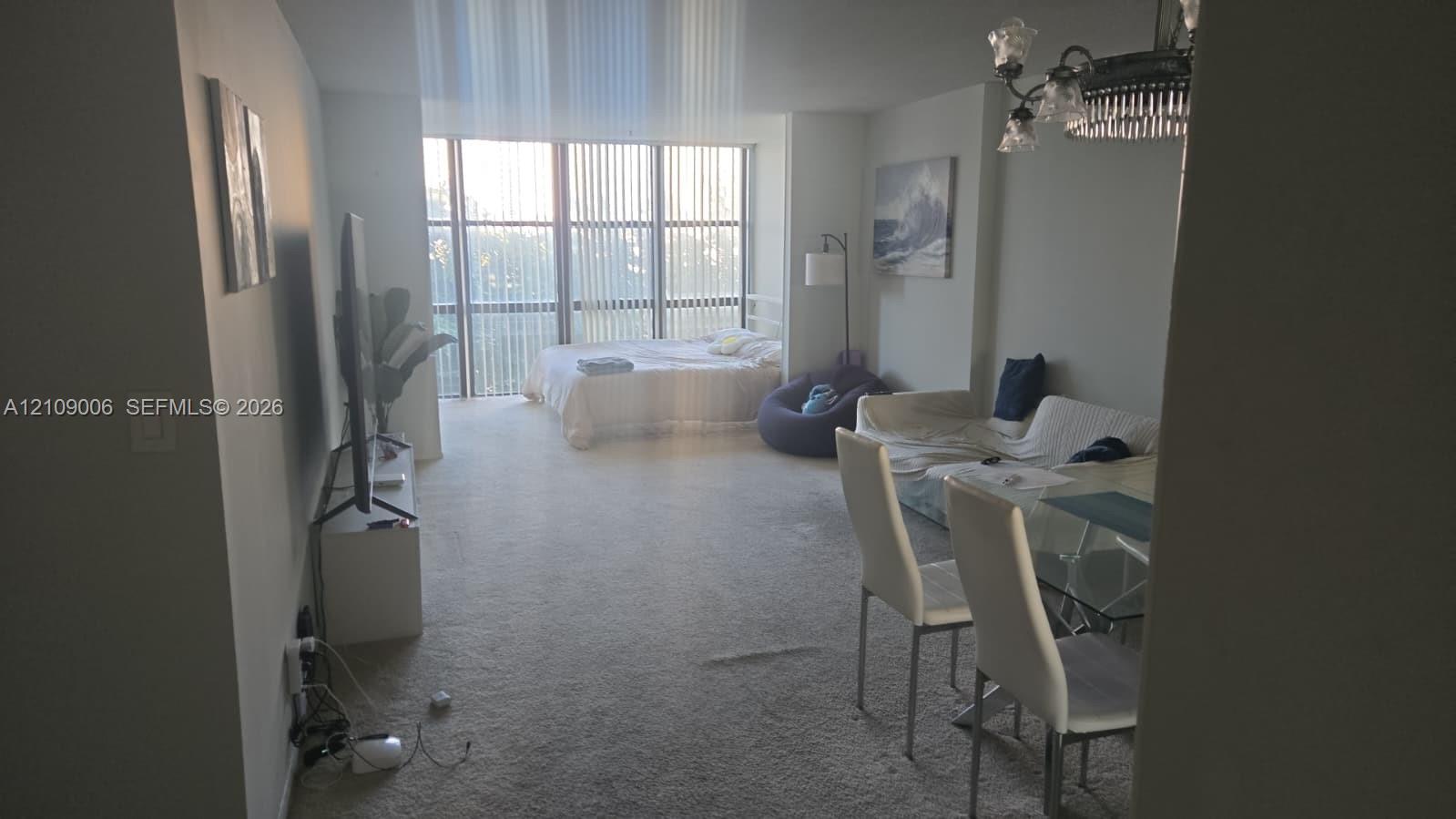 Floor-to-ceiling windows with vertical blinds and a traditional multi-arm chandelier