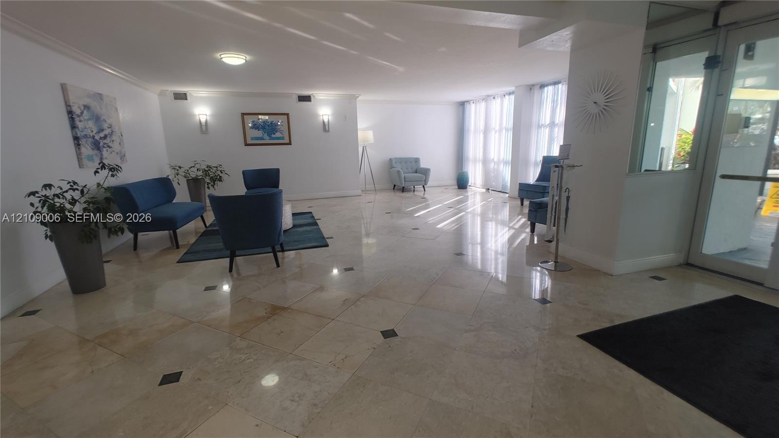 Polished stone flooring with decorative inlay accents, expansive floor-to-ceiling windows, and wall-mounted sconce lighting