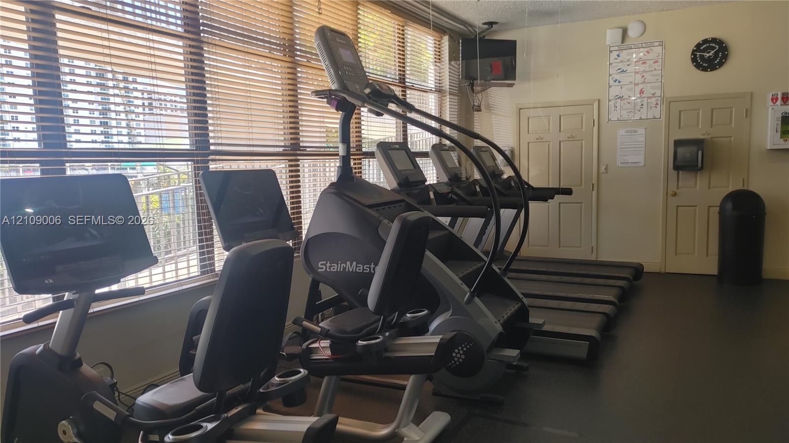 Fitness center featuring wall-to-wall windows with horizontal blinds and resilient flooring