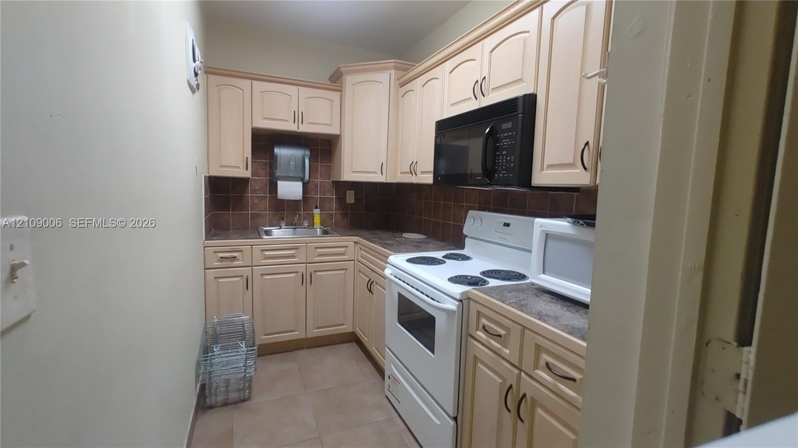 Kitchen featuring light-finish cabinetry, tile backsplash, built-in microwave, and tile flooring