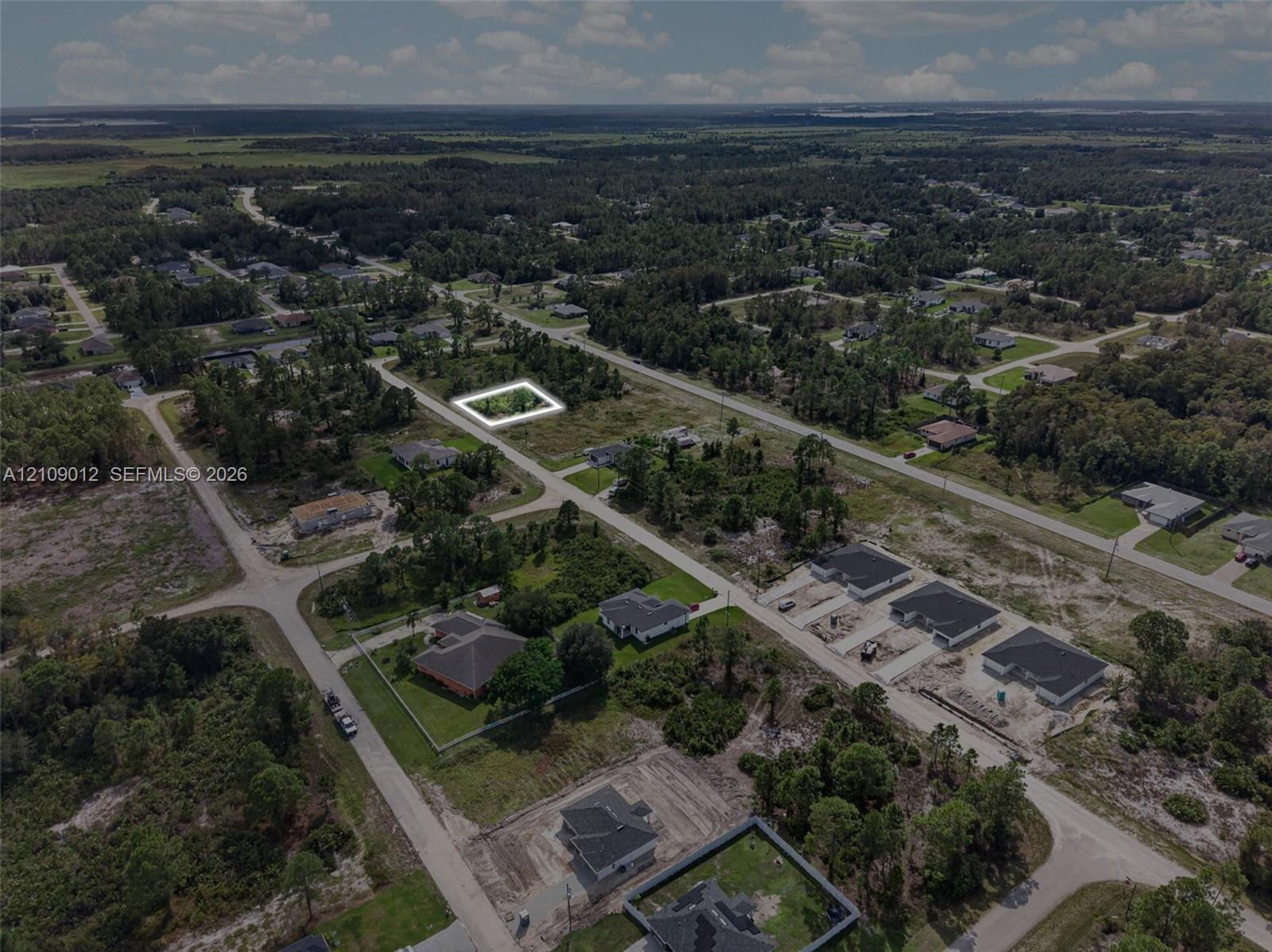Aerial perspective of a corner lot featuring level topography, native vegetation, and surrounding paved roadways