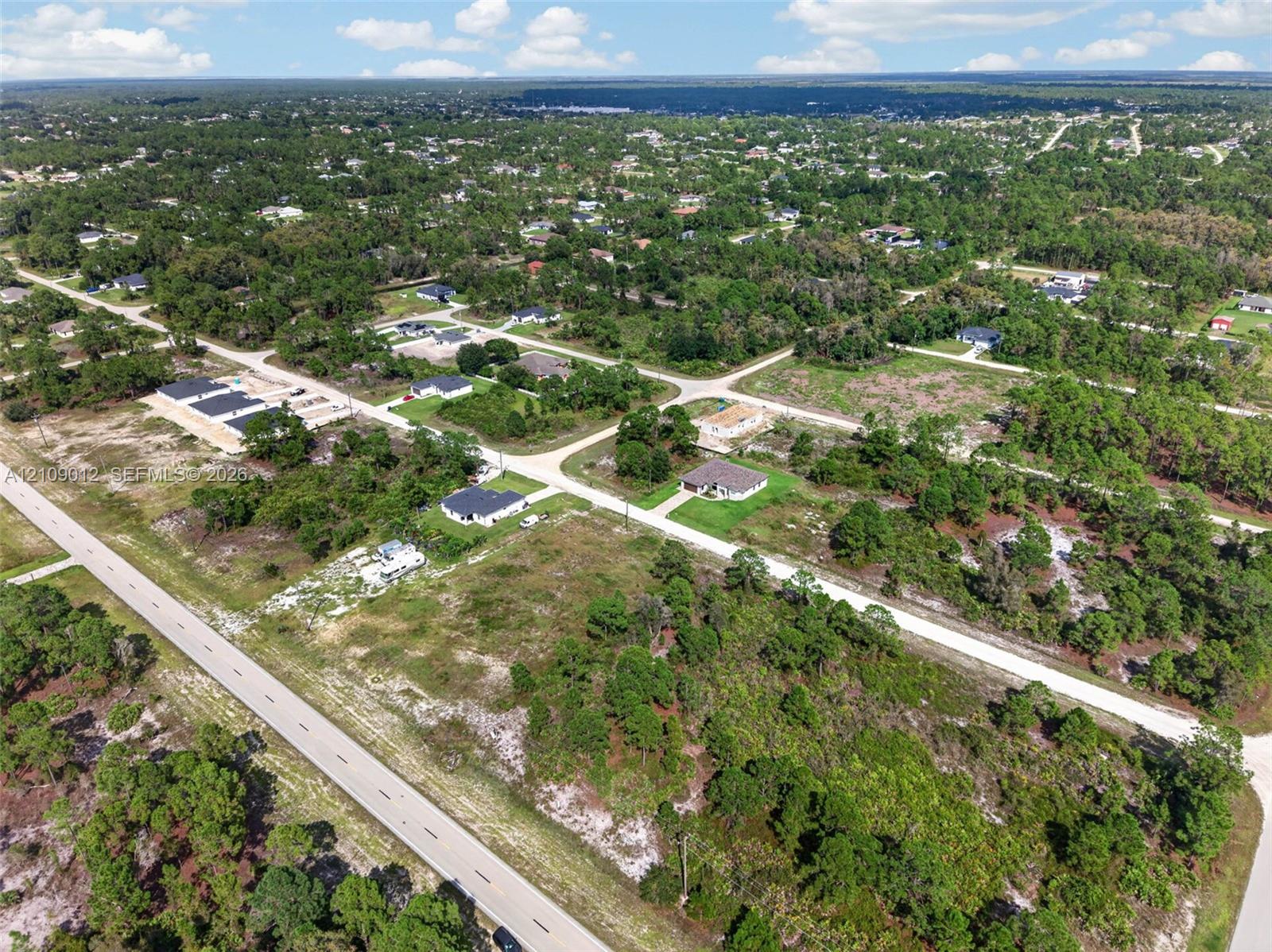 Aerial perspective featuring expansive undeveloped land parcel, paved road access, and surrounding native vegetation