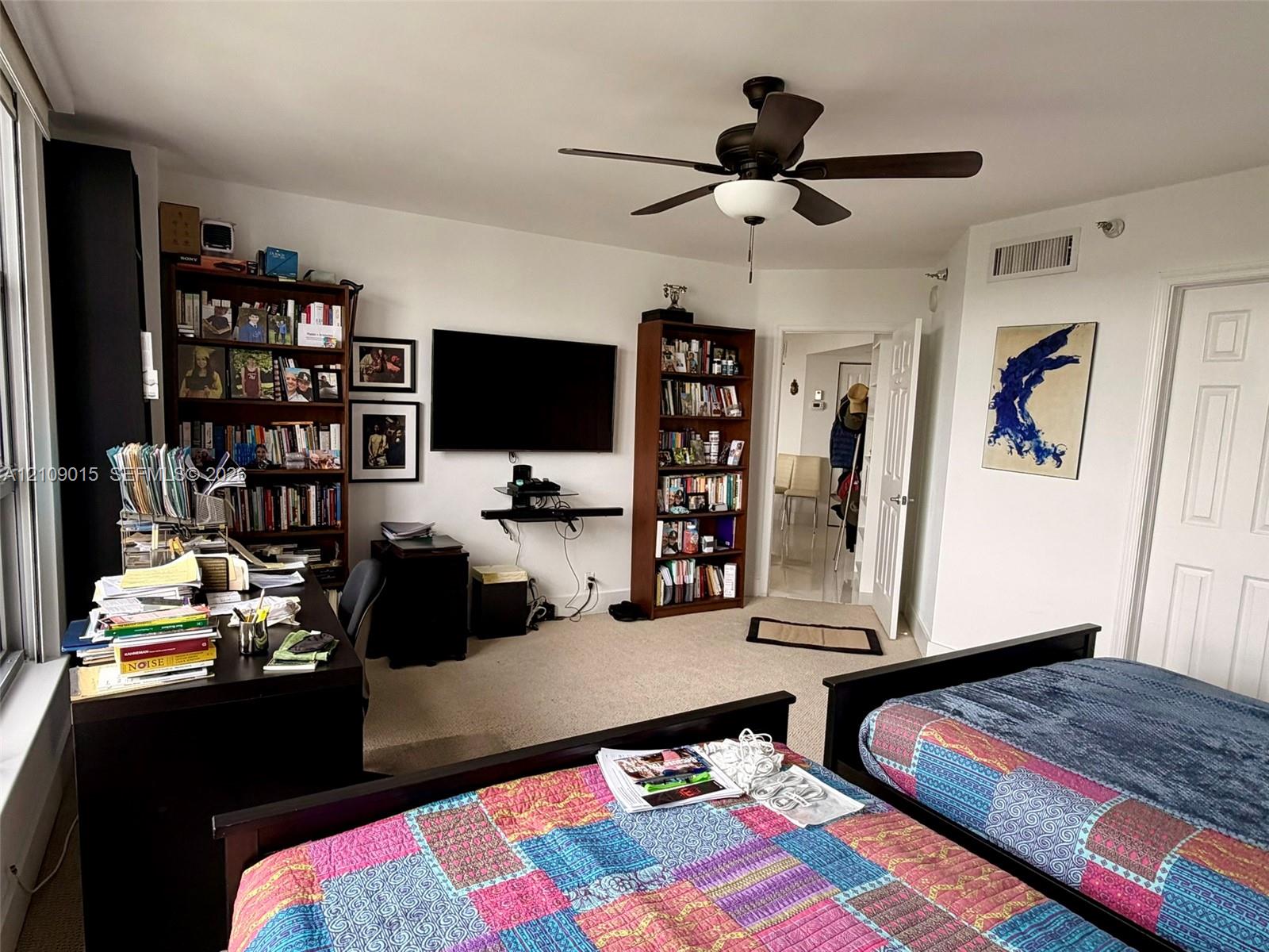 Spacious interior featuring neutral carpeting, a central ceiling fan with integrated lighting, and multiple paneled interior doors