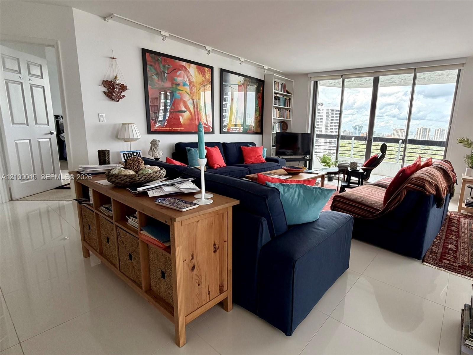 Living space featuring large-format tile flooring, floor-to-ceiling glass doors, integrated track lighting, and built-in shelving Living space featuring large-format tile flooring, floor-to-ceiling glass doors, integrated track lighting, and built-in shelving