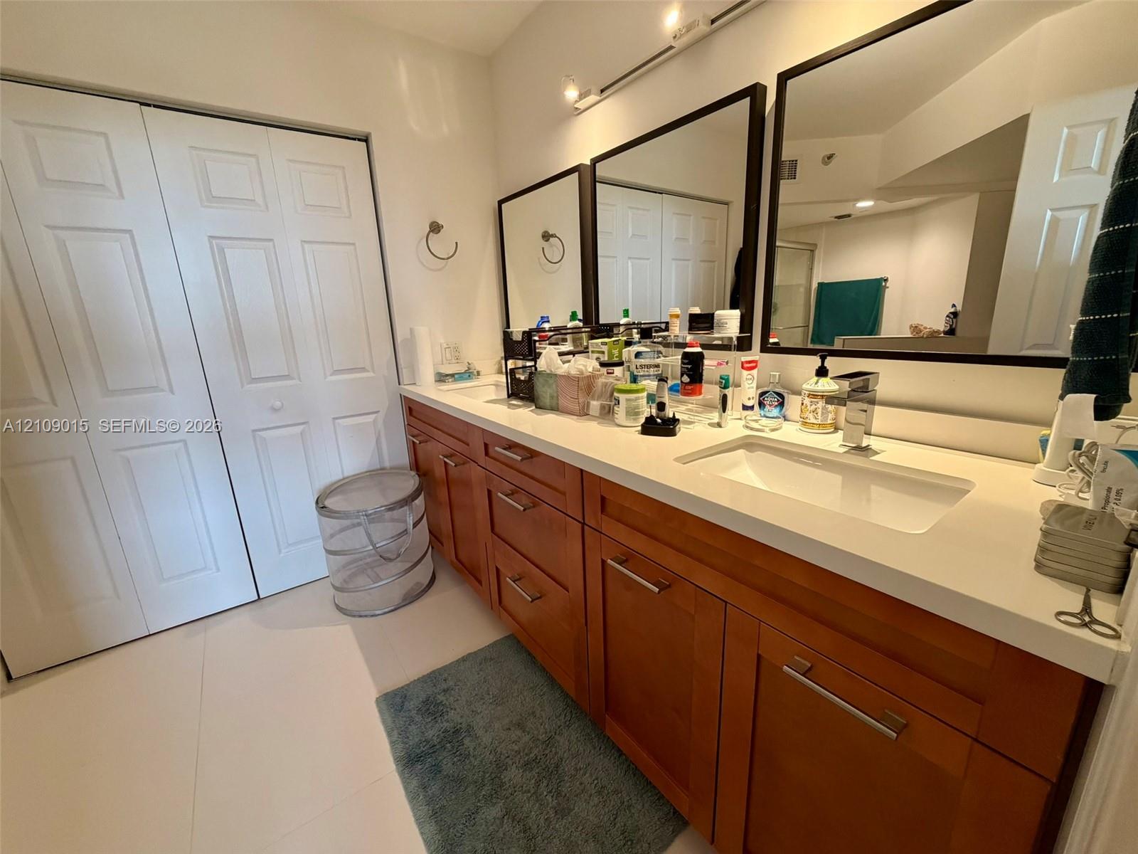 Extended wood-finish vanity with a stone countertop, dual integrated rectangular sinks, modern chrome fixtures, and three framed vanity mirrors
