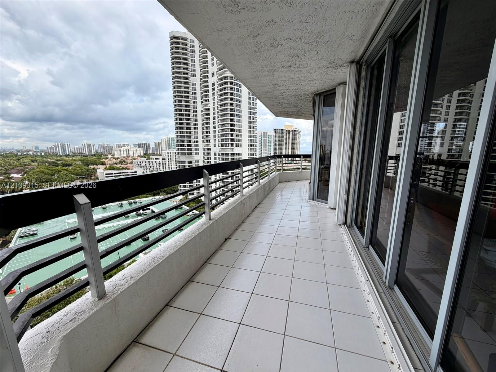 Spacious balcony featuring tile flooring, a horizontal metal railing, and floor-to-ceiling glass sliding doors