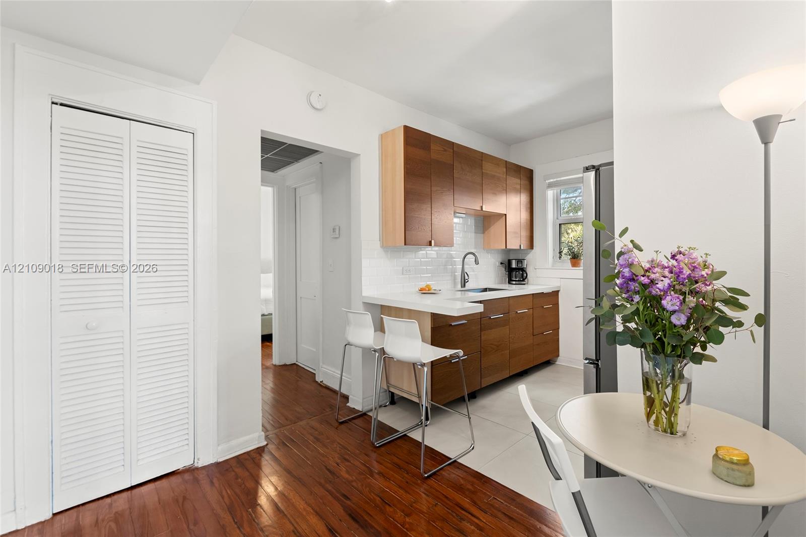Kitchen featuring wood-finish cabinetry, white solid-surface countertops, a subway tile backsplash, and wood-finish flooring