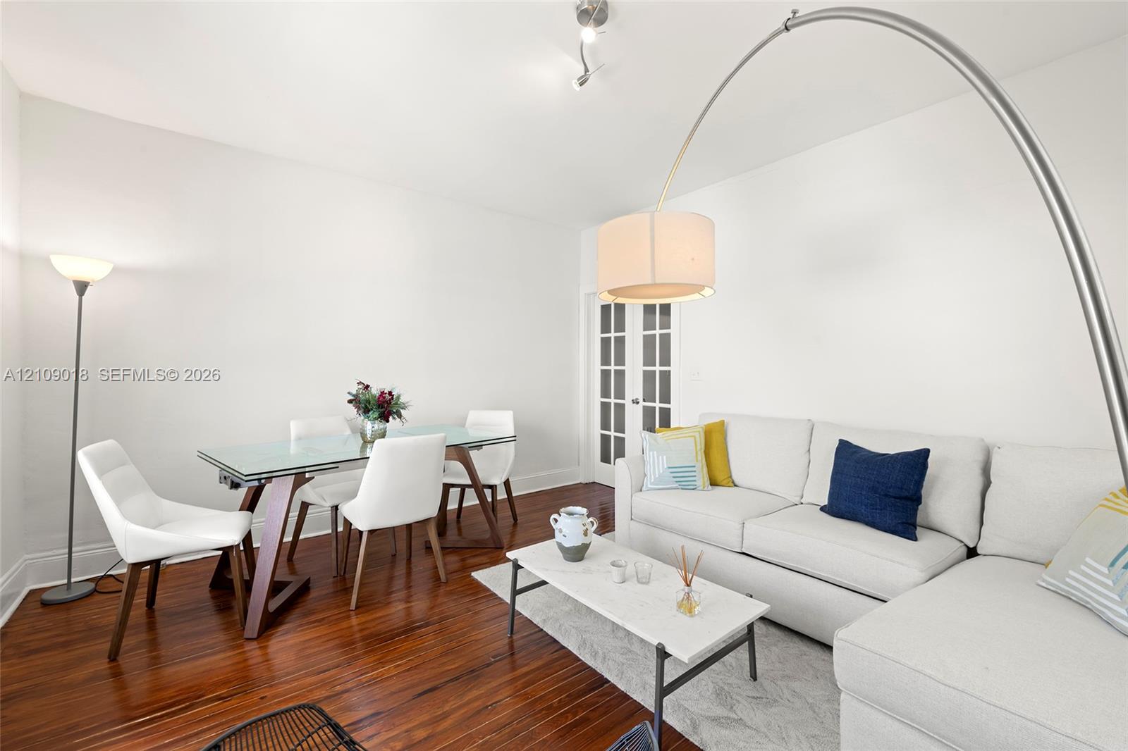 Wood-finish flooring, white walls, and French doors featuring glass panes