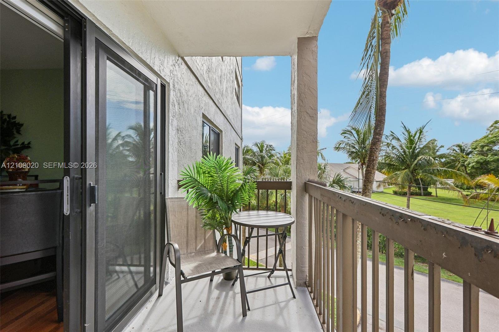 Covered balcony featuring sliding glass doors, a concrete floor surface, and metal railing