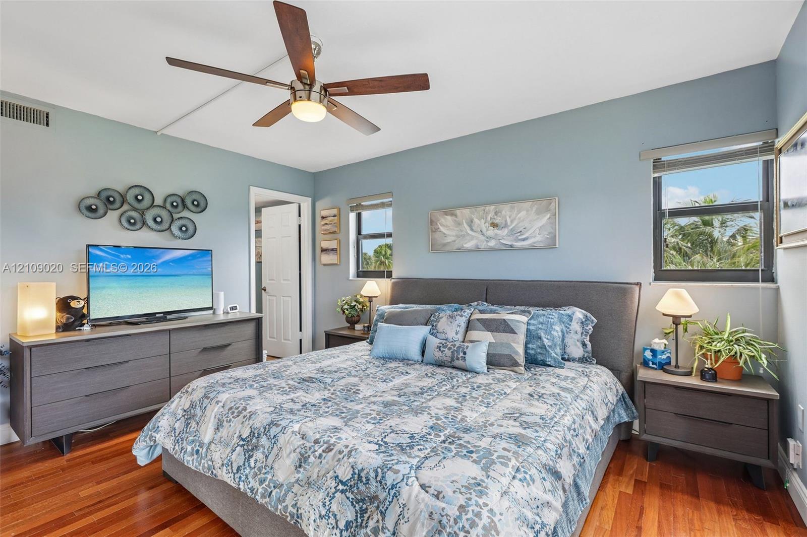Wood-finish flooring, multi-blade ceiling fan with integrated lighting, and dual windows
