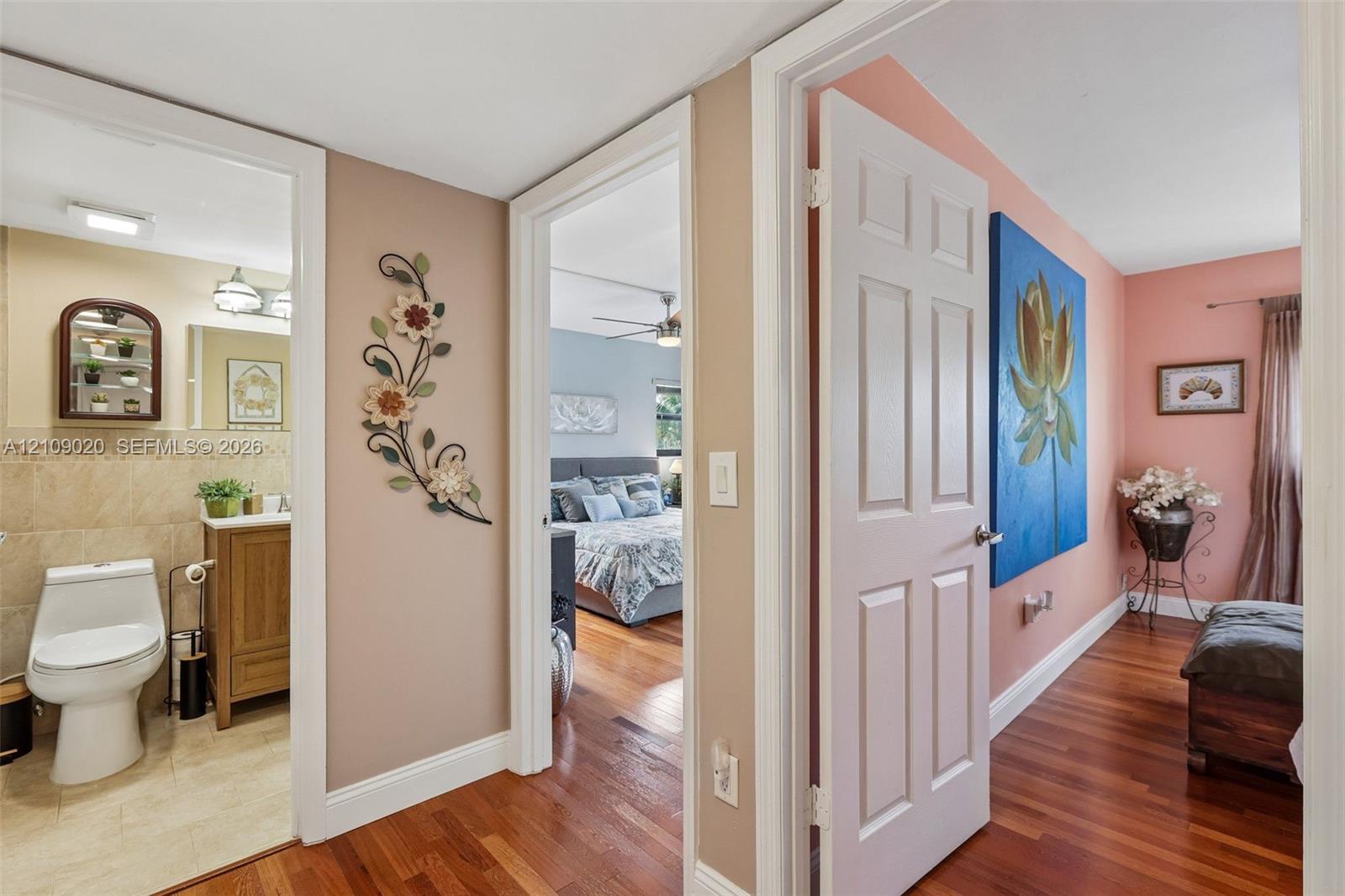 Hallway featuring wood-finish flooring, a bathroom with a wood-finish vanity, and a six-panel interior door