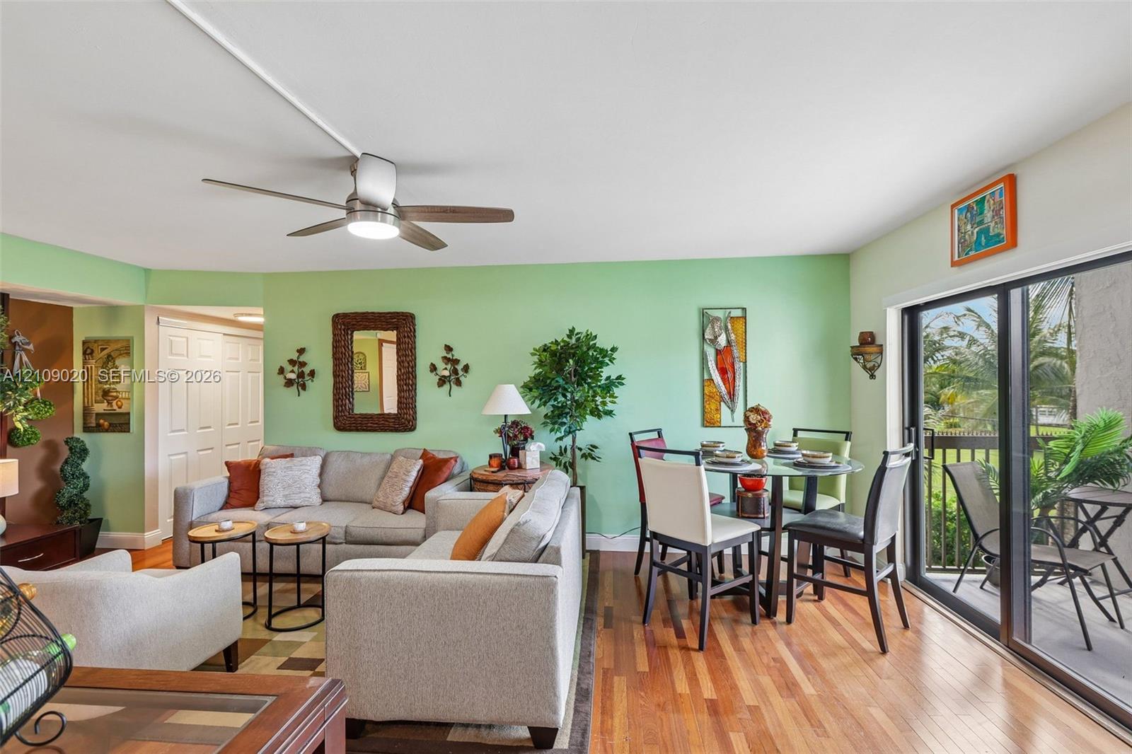 Open-concept interior featuring wood-finish flooring, a ceiling fan with integrated lighting, and sliding glass doors providing access to the exterior