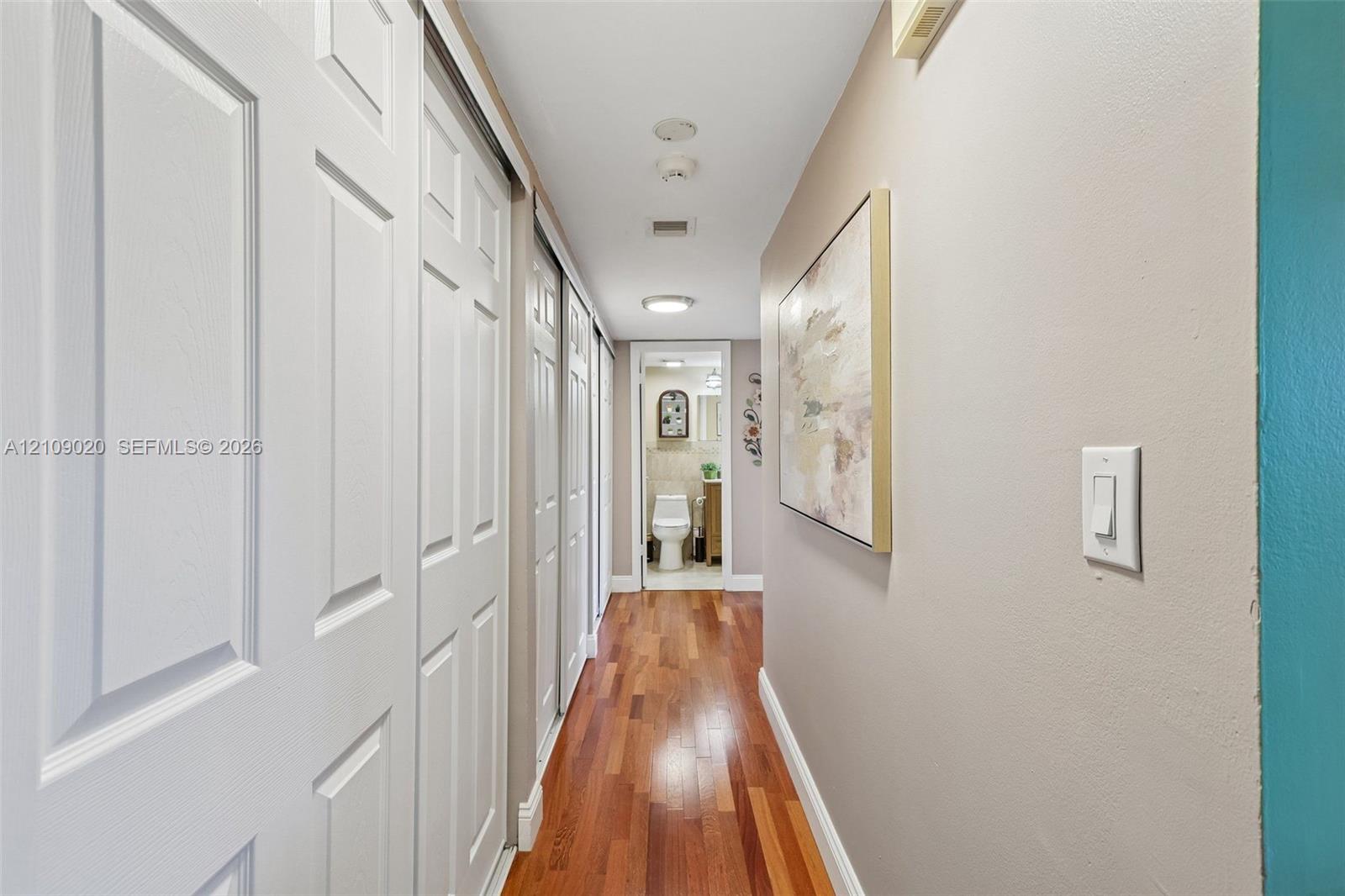 Hallway featuring wood-finish flooring, dual sliding-panel closet doors, and recessed lighting