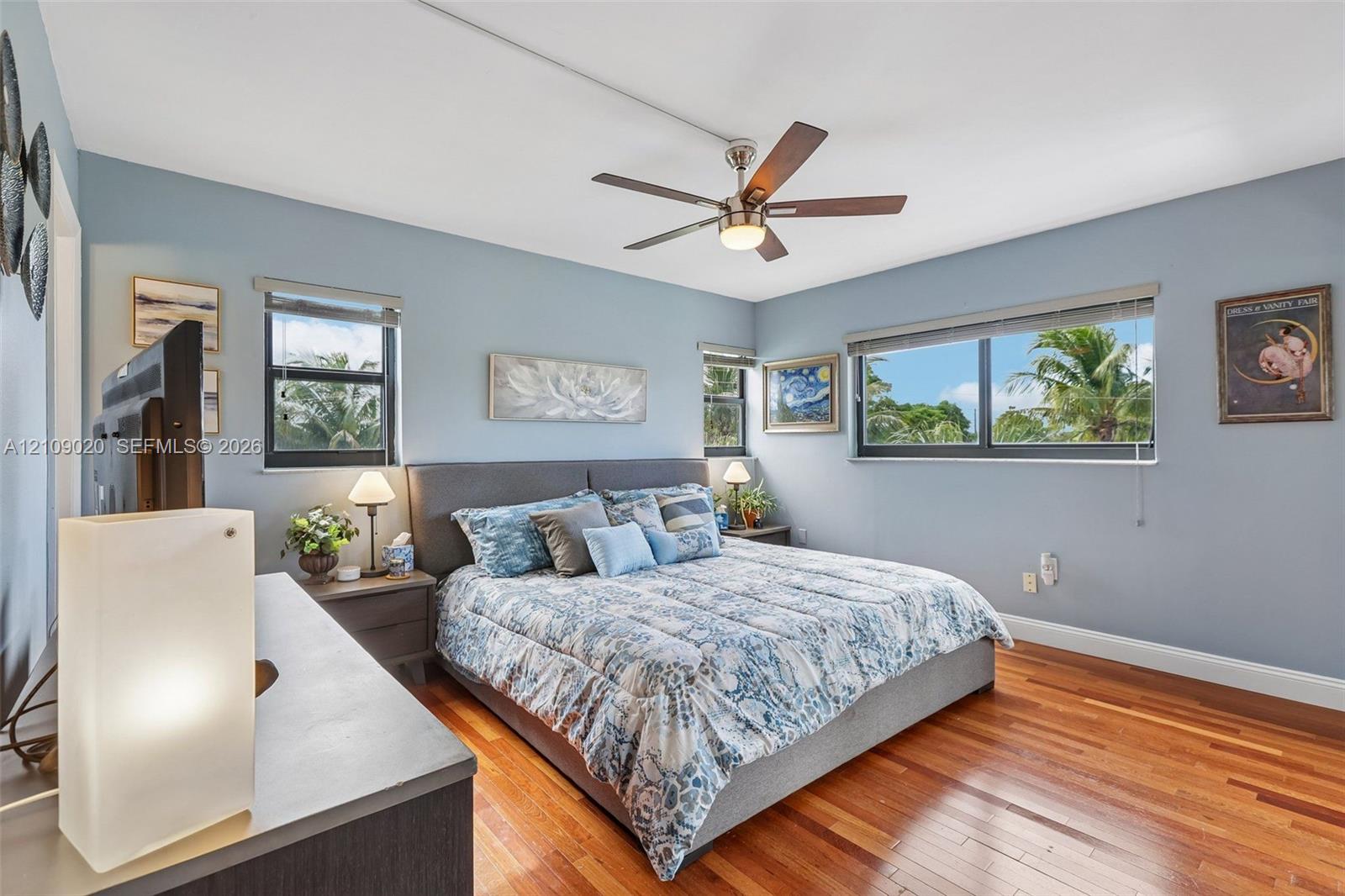 Wood-finish flooring, multi-pane windows with horizontal blinds, and a multi-blade ceiling fan with integrated lighting