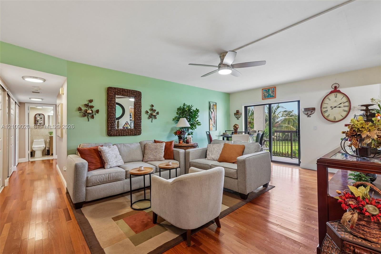 Living area featuring wood-finish flooring, a ceiling fan with integrated lighting, and sliding glass doors