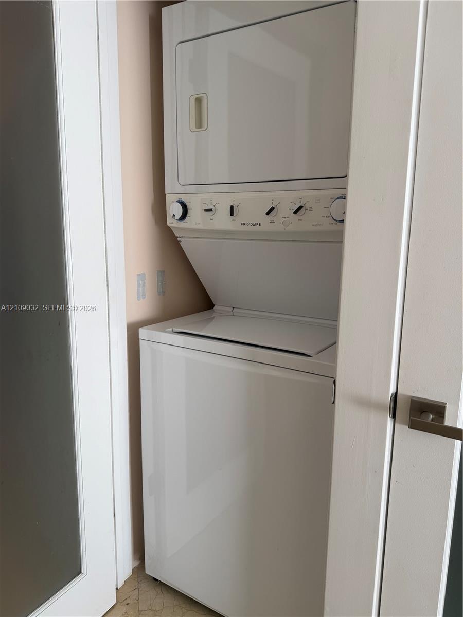 Stacked white laundry unit featuring a top-loading washer and front-loading dryer with analog dial controls