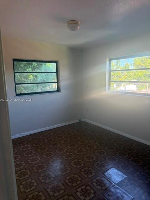 Interior room featuring neutral-toned walls, patterned tile flooring, and two horizontal slider windows