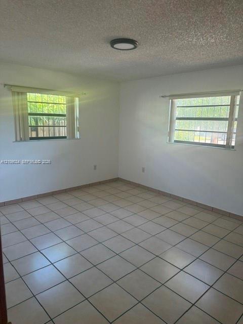 Neutral-toned tile flooring, dual windows with exterior security bars, and a flush-mount ceiling light fixture