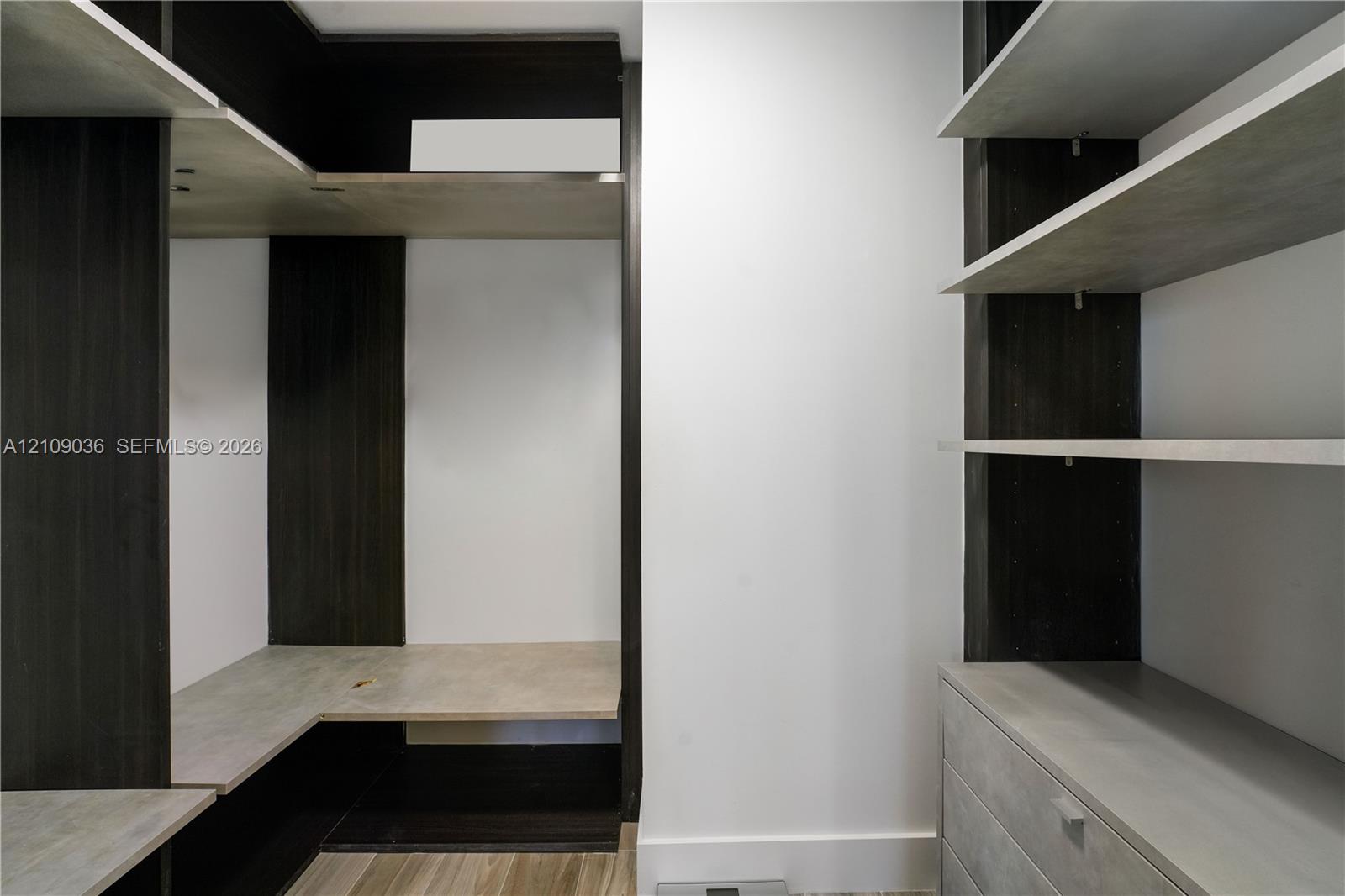 Custom built-in storage system featuring dark wood-tone cabinetry, multiple open shelving tiers, integrated drawer units, and light-toned horizontal surfaces