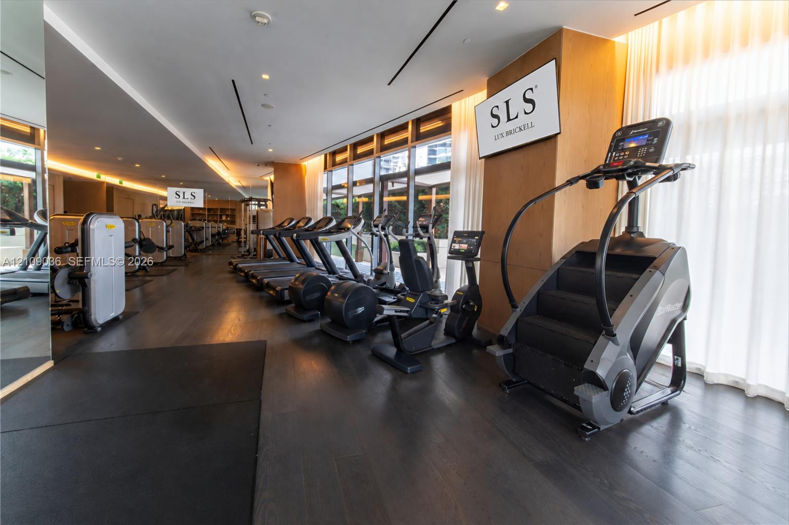 Fitness center featuring dark wood-finish flooring, floor-to-ceiling windows, full-length wall mirrors, and recessed ceiling lighting