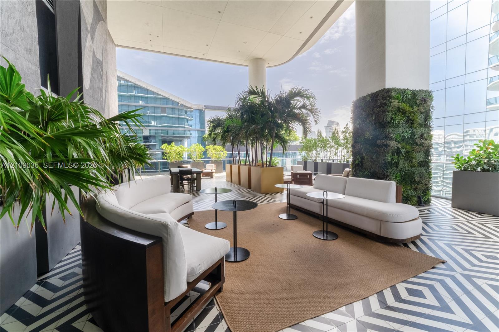 Covered terrace featuring geometric patterned floor tiling, a living wall installation, and glass paneled railings