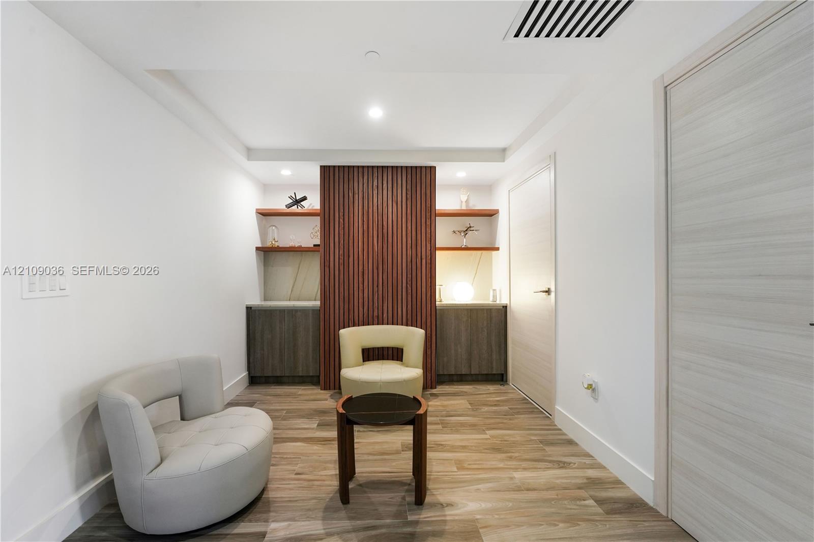 Custom built-in cabinetry with flat-panel doors, vertical slat wood accent feature, integrated floating shelving, recessed ceiling lighting, and wood-finish flooring
