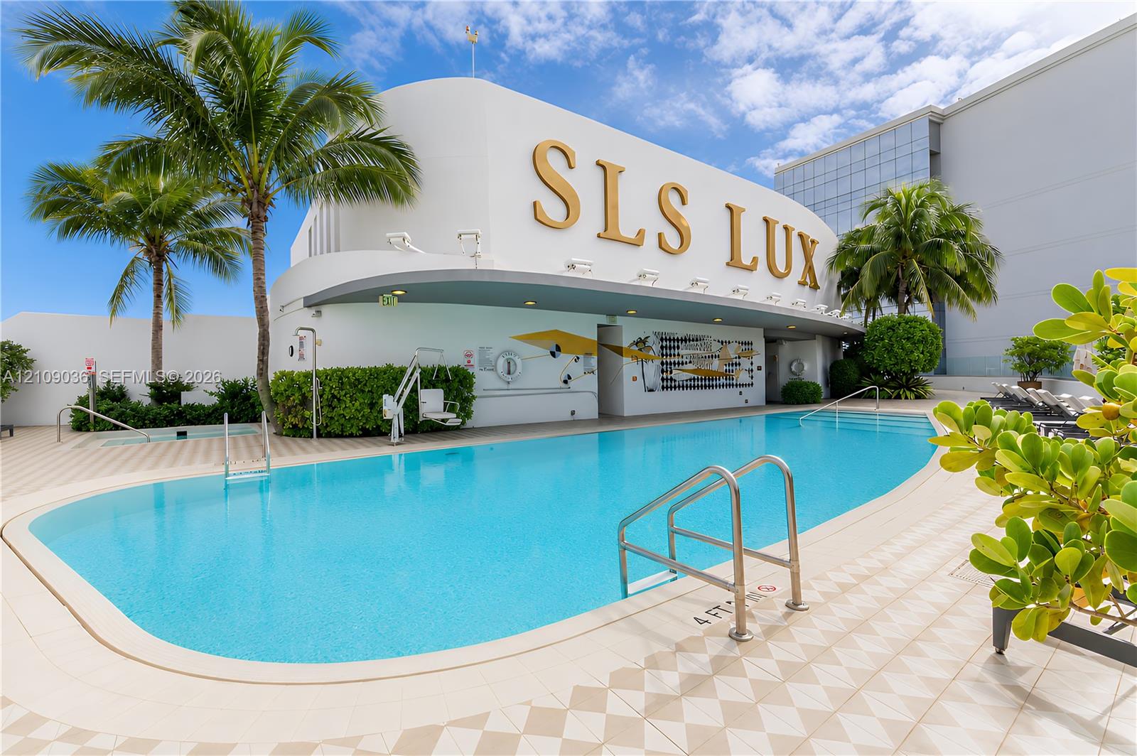 Outdoor swimming pool featuring a curved concrete deck, metallic handrails, built-in wall mural, and mature palm trees