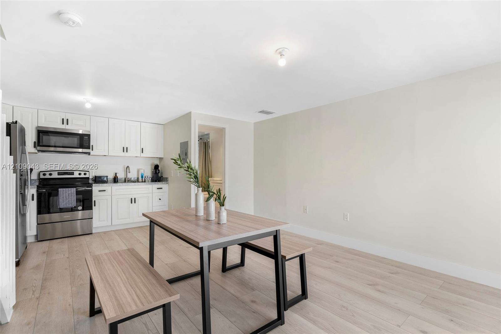 Kitchen featuring white shaker-style cabinetry, stainless steel appliances, and wood-finish flooring