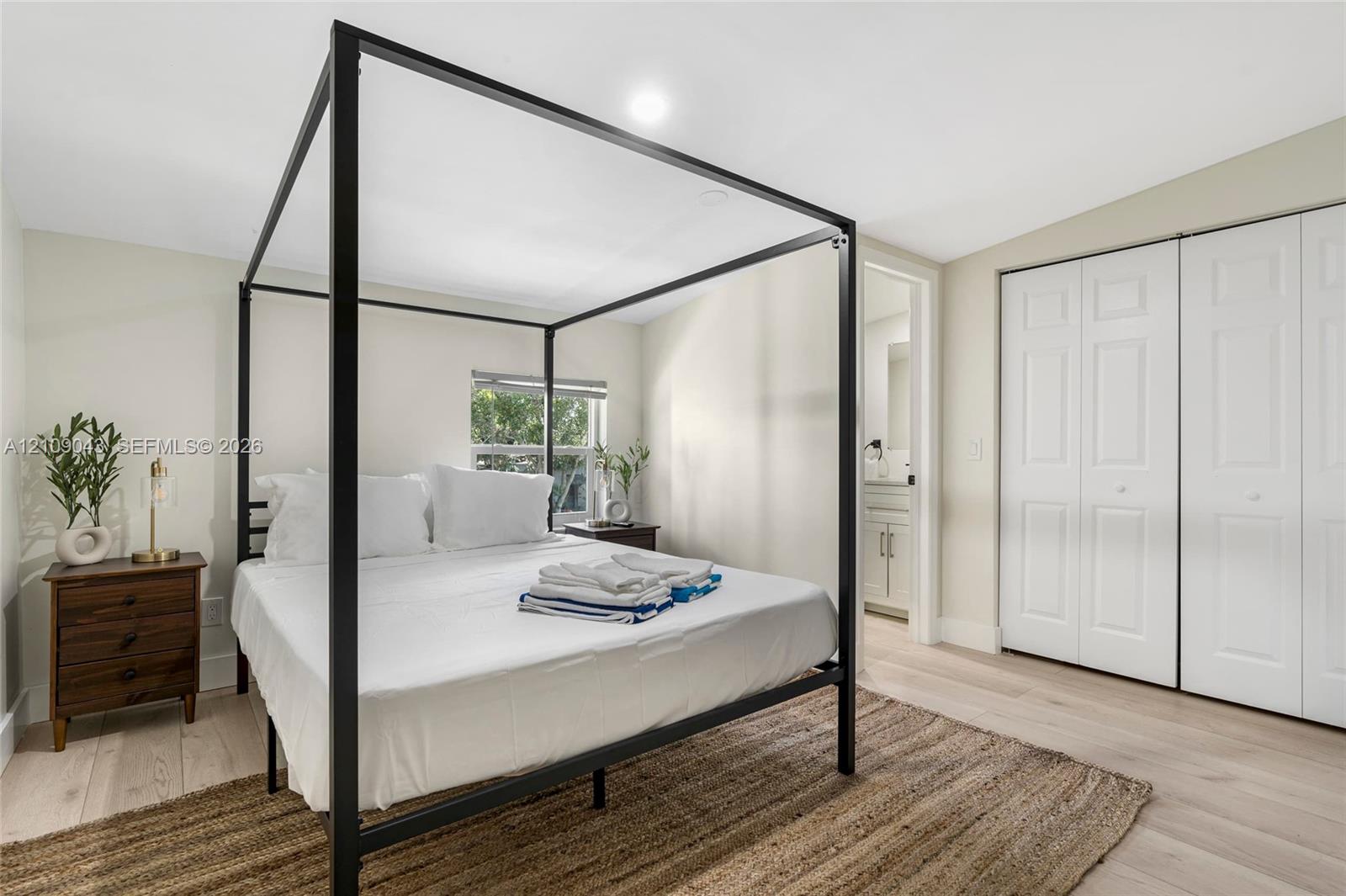 Light-toned wood-finish flooring, dual-panel white closet doors, and recessed ceiling lighting
