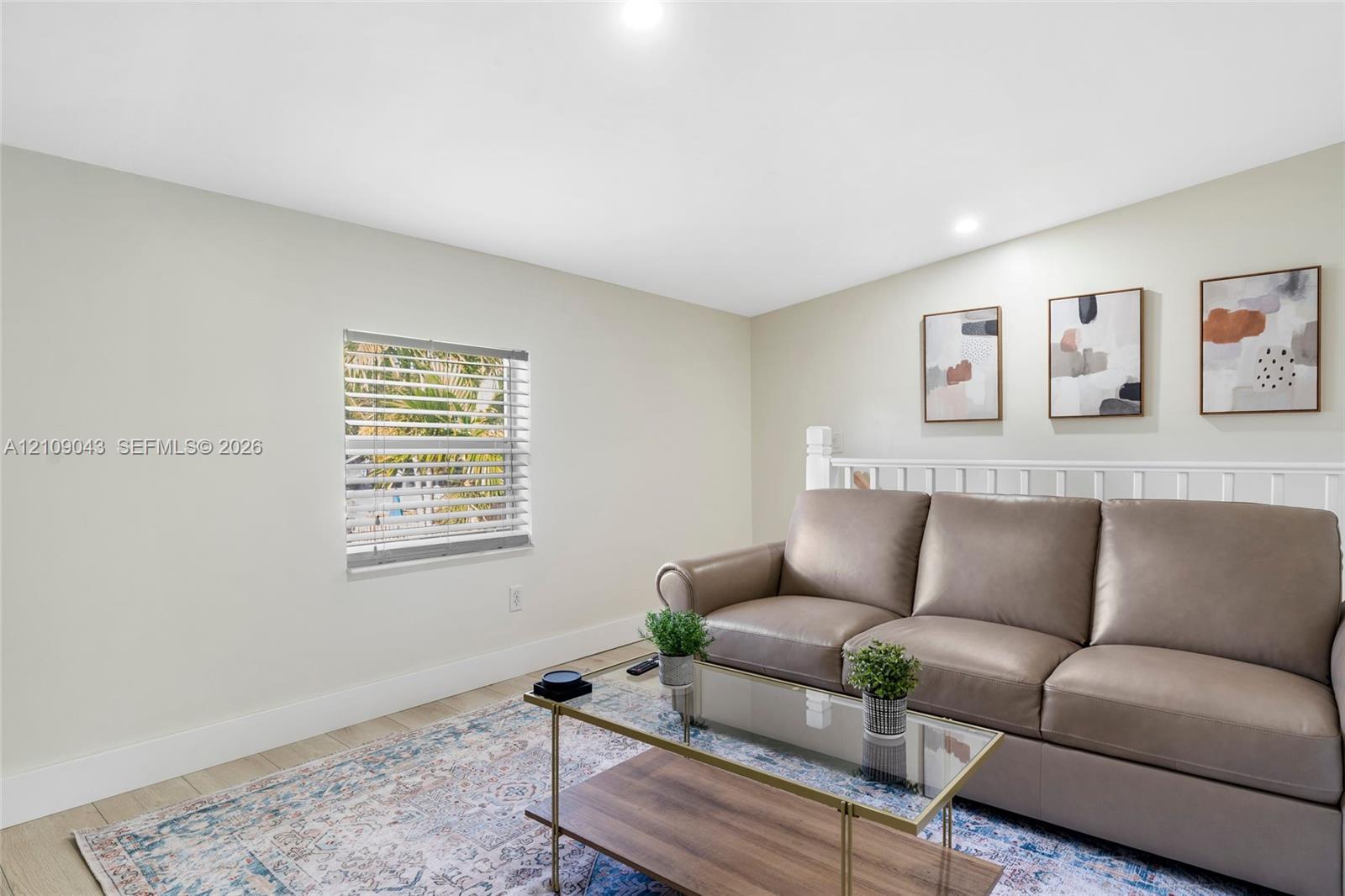 Neutral interior featuring wood-finish flooring, recessed lighting, and a white wooden stair railing