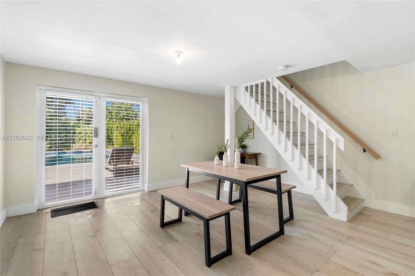 Wood-finish flooring, white staircase with handrail, and full-glass double doors