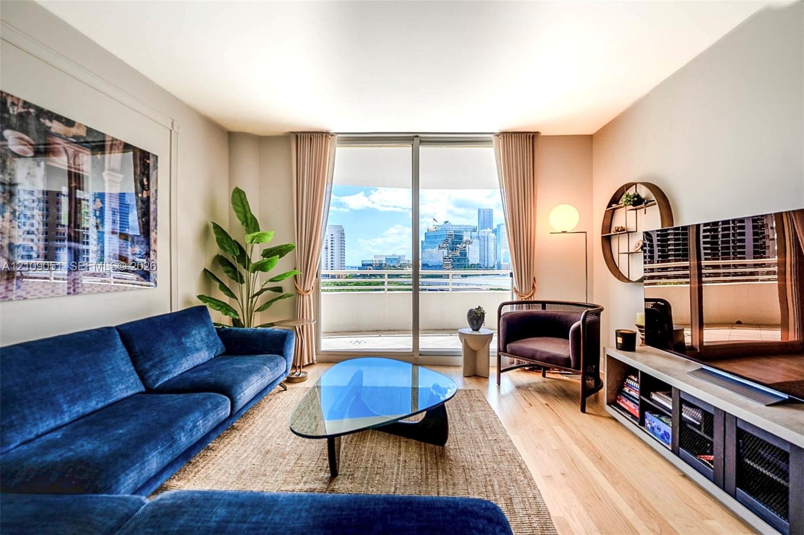 Living area featuring floor-to-ceiling sliding glass doors, a private balcony, and light wood-finish flooring