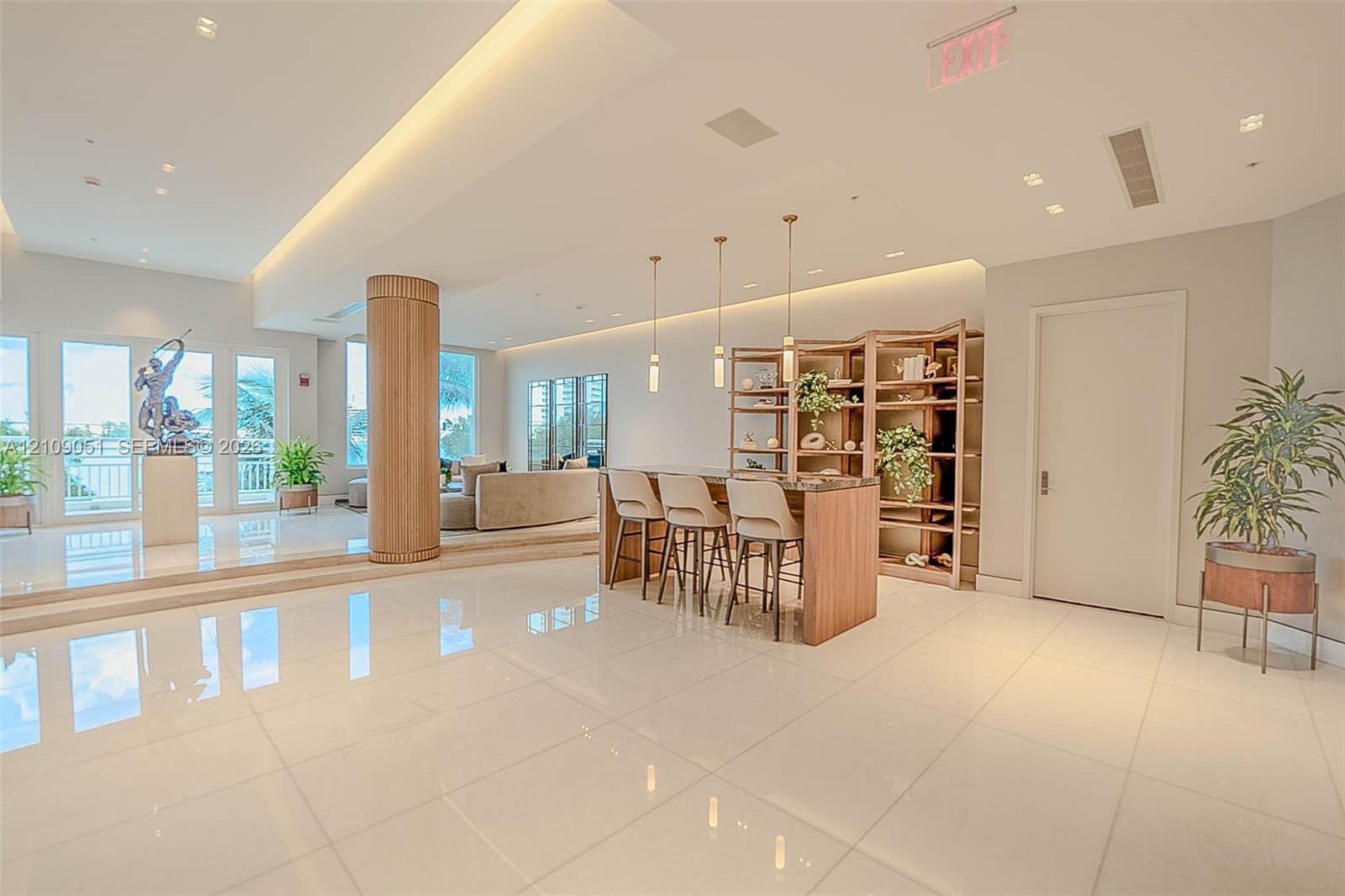 Spacious common area featuring polished tile flooring, tray ceilings with recessed lighting, a wood-wrapped structural column, and custom built-in shelving
